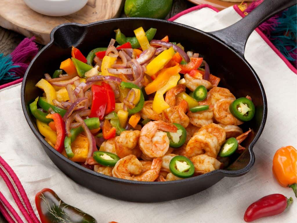 Cast iron skillet filled with shrimp and vegetables.